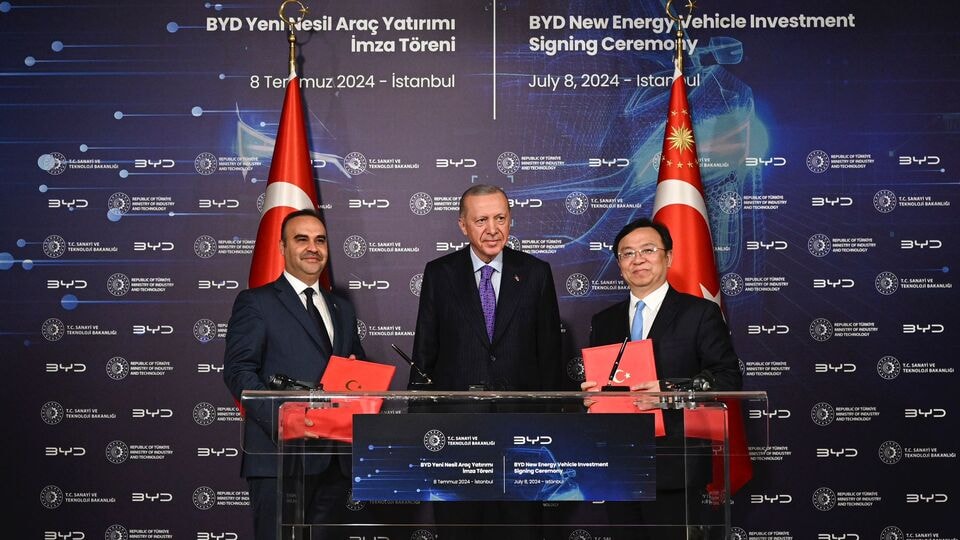 BYD Yeni Nesil Araç Yatırımı imza töreninde Türkiye ve Çin bayrakları önünde üç kişinin yer aldığı fotoğraf.