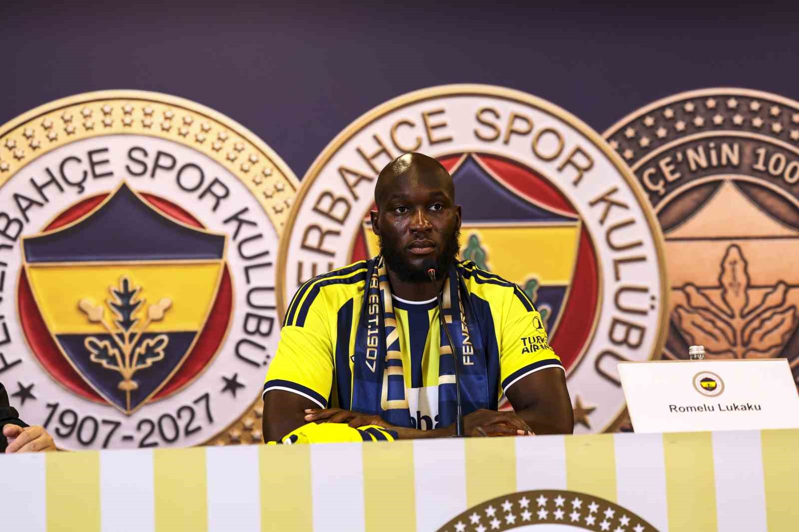 Romelu Lukaku, Fenerbahçe logosu önünde basın toplantısı masasında oturuyor.