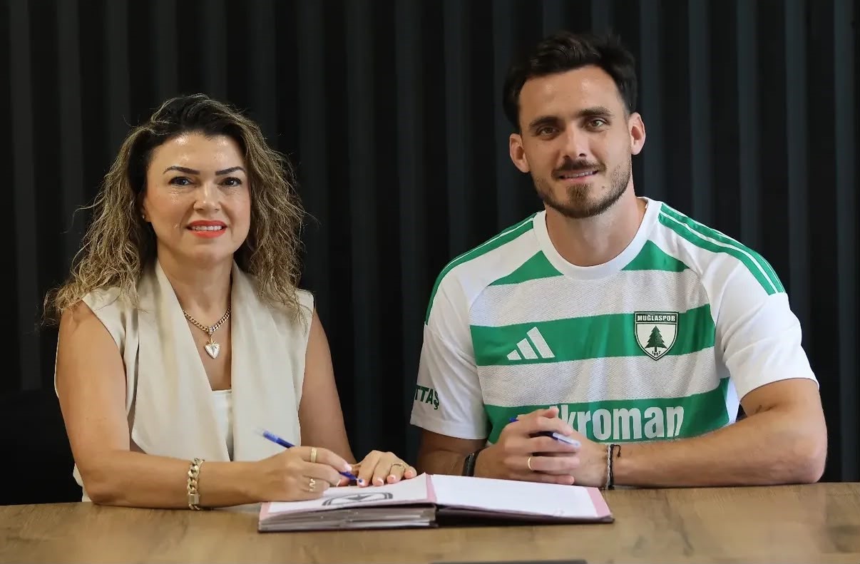 Luis Enrique Del Pino Mago ve Gül Tütüncü, sözleşme imza masasında kameraya poz veriyor.