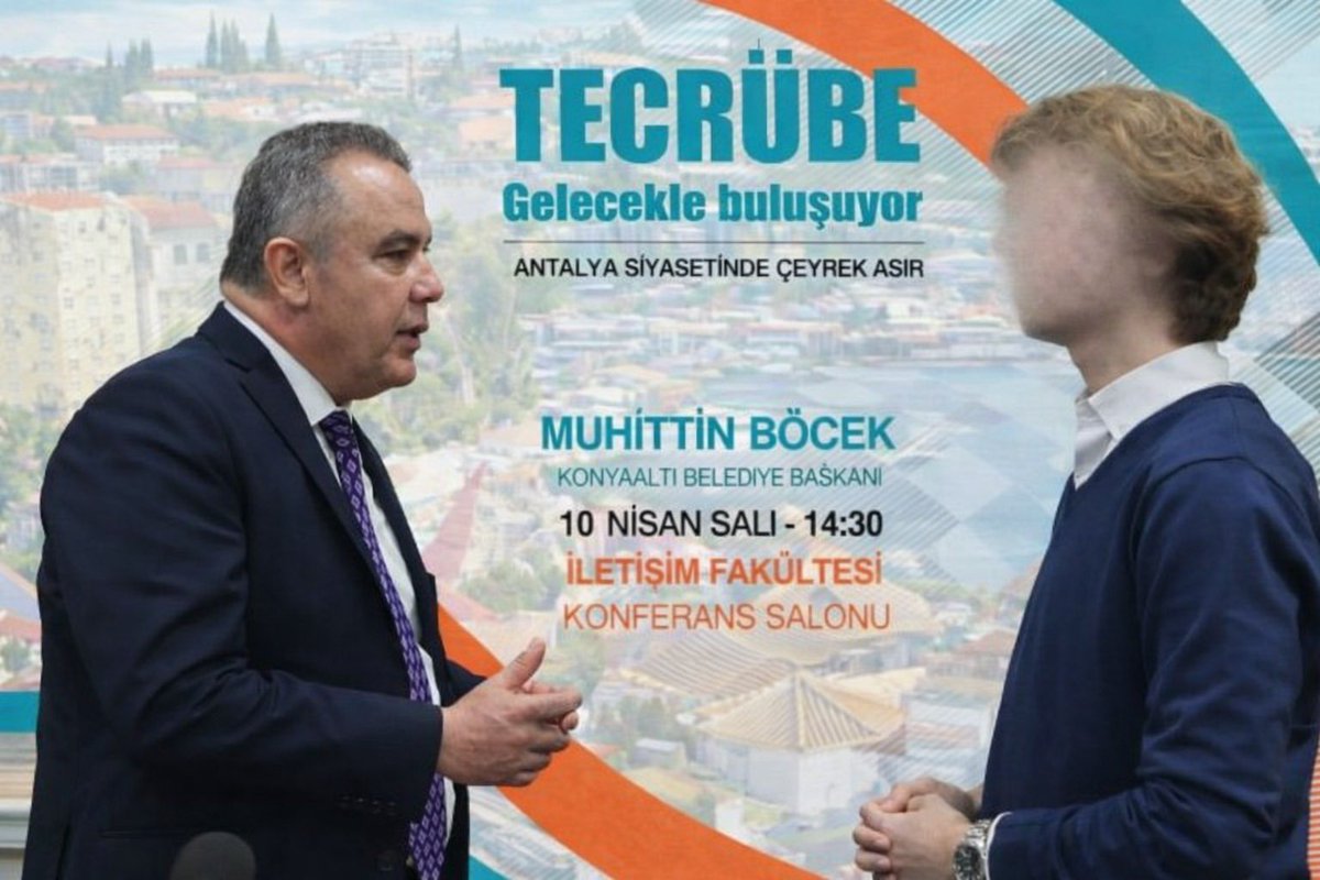 Muhittin Böcek isminin yer aldığı bir etkinlik afişi önünde iki kişinin görüldüğü fotoğraf.