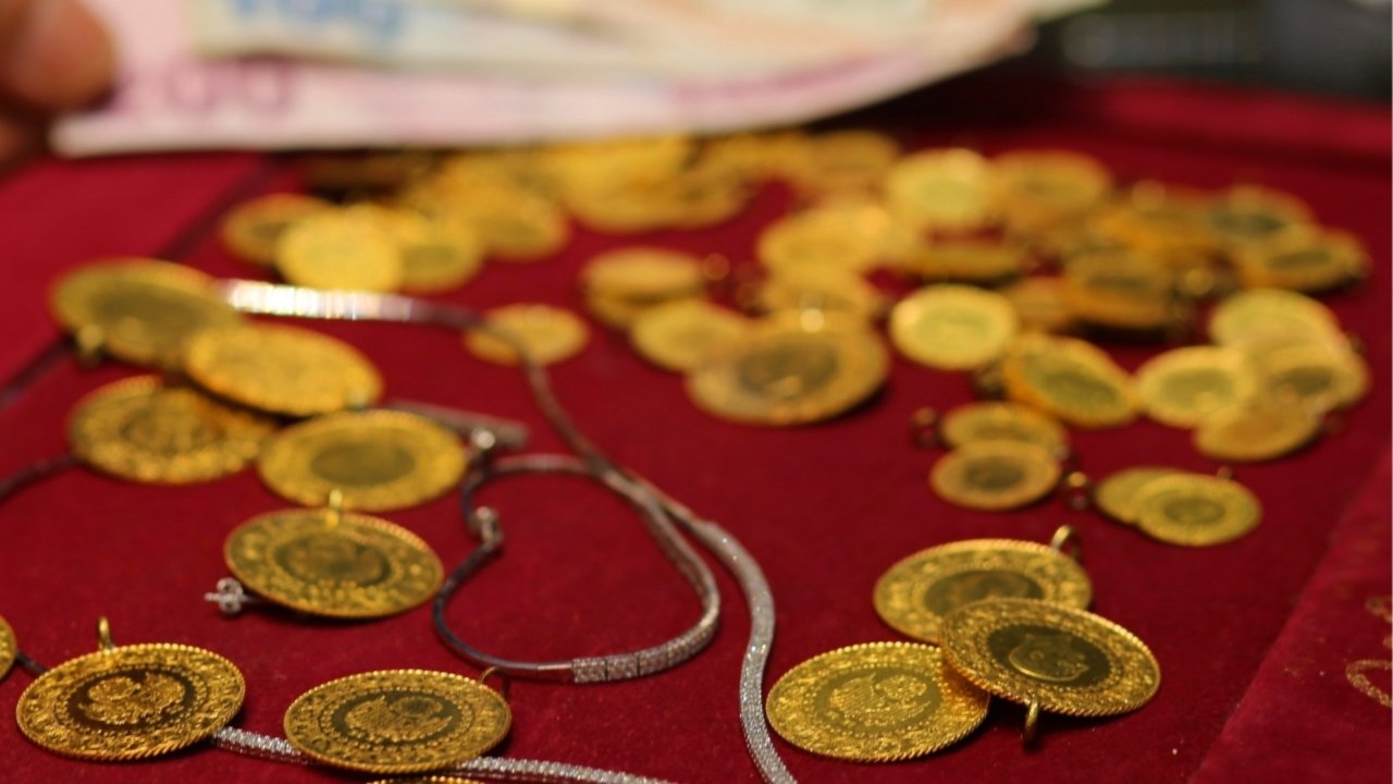 Kırmızı vitrin üzerinde altın takılar ve arka planda banknotlar