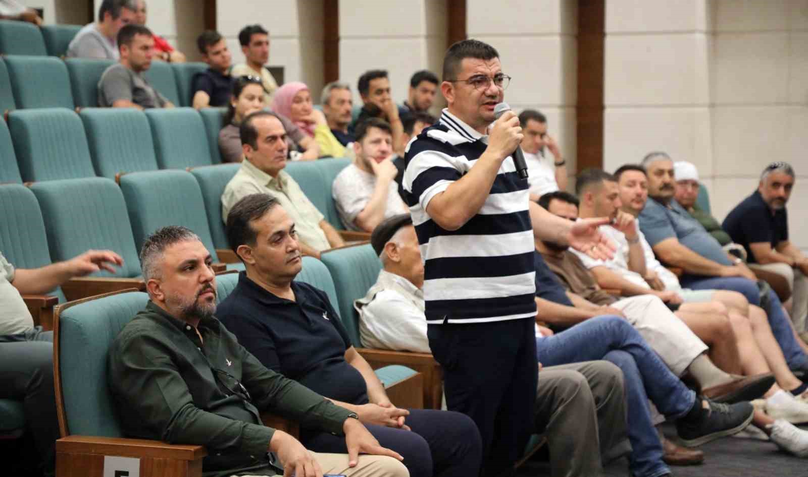 Muğla’da proje tanıtım toplantısında mikrofonla konuşan bir vatandaş ve salondaki katılımcılar.