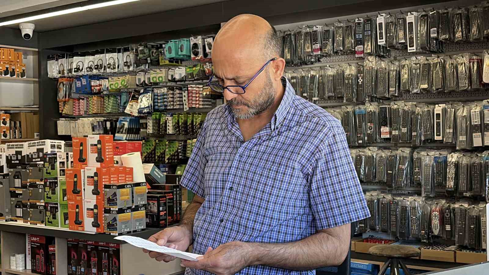 Elektronik ürünlerin bulunduğu bir iş yerinde Kemal Kalem elindeki kâğıda bakıyor.