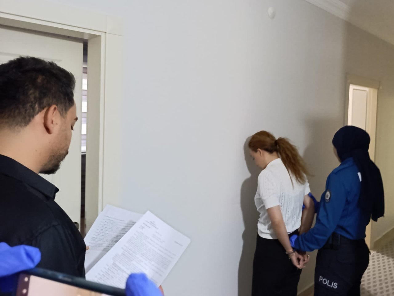 Polis ekiplerinin bir daire içinde işlem yaptığı ve bir şüpheliyi götürdüğü görüntü.