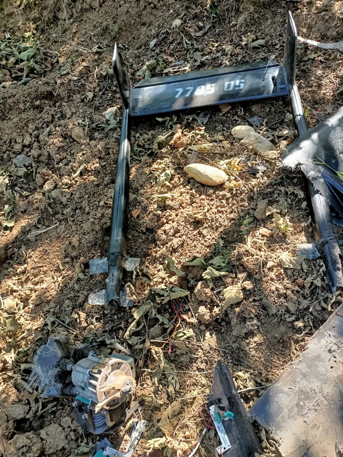 Fındık bahçesindeki toprak üzerinde siyah renkli parçalar, kablolar ve mekanik aksam yer alıyor.