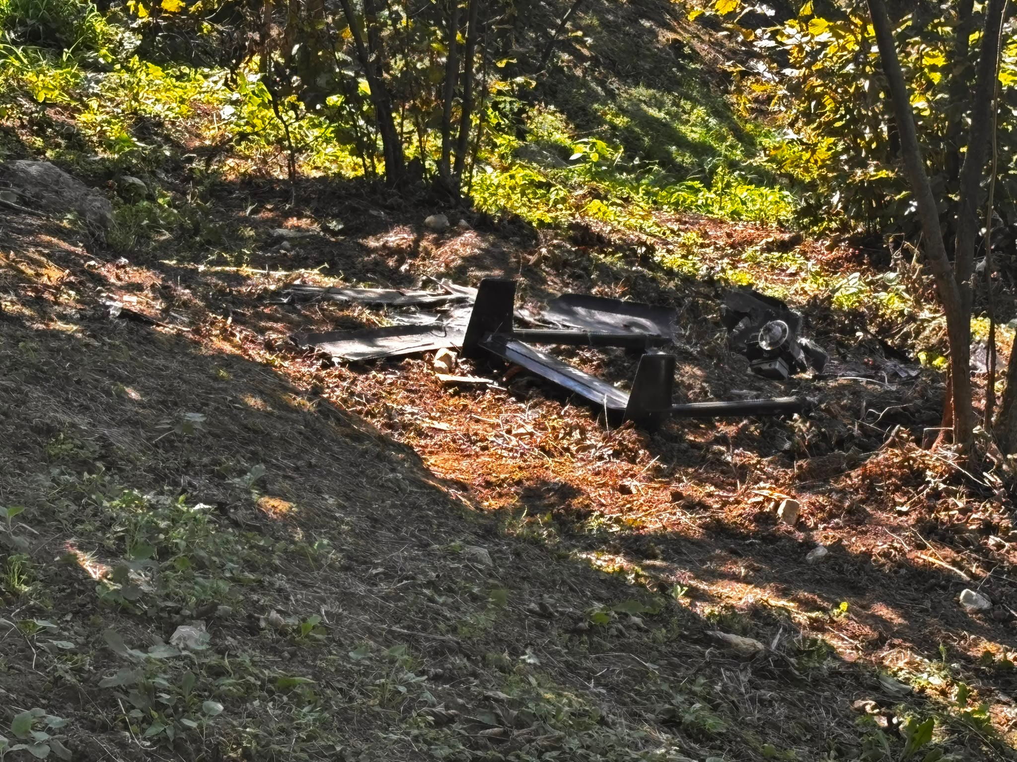 Ağaçlık alandaki fındık bahçesinde siyah renkli parçalanmış hava aracı benzeri kalıntılar bulunuyor.