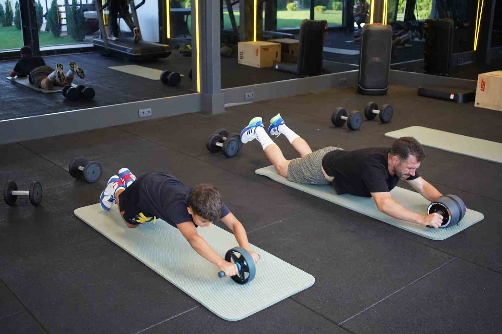Kürşat Kiraz ve öğrencisi spor salonunda egzersiz matları üzerinde çalışıyor.