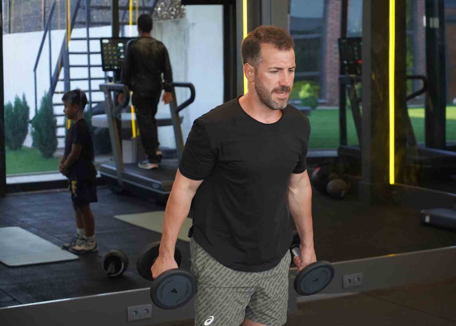 Kürşat Kiraz spor salonunda dambıllarla çalışırken görüntüleniyor.