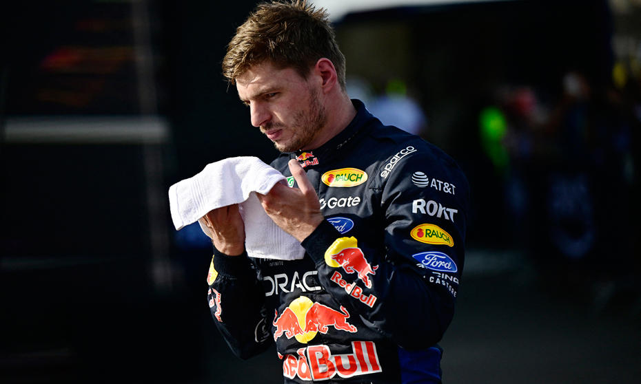 Max Verstappen Red Bull yarış kıyafetiyle padokta havluyla yüzünü siliyor.