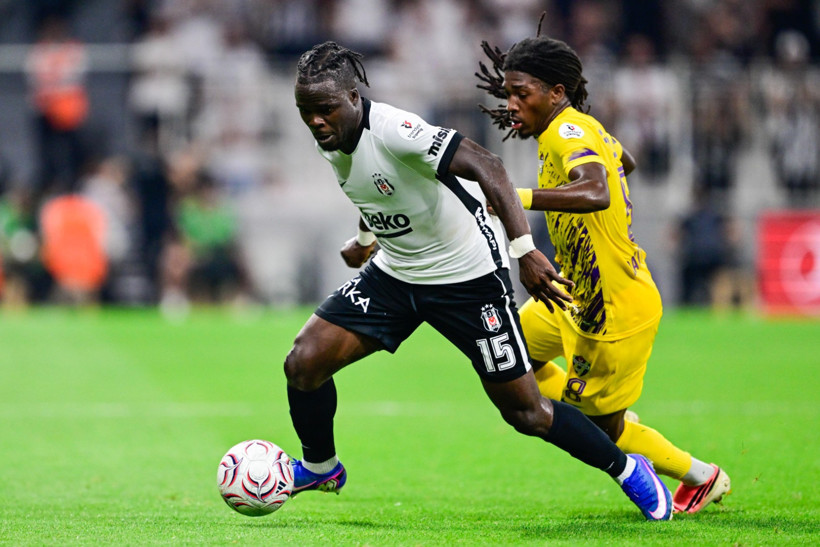 Beşiktaşlı futbolcu, Eyüpsporlu rakibinin baskısı altında top sürüyor.