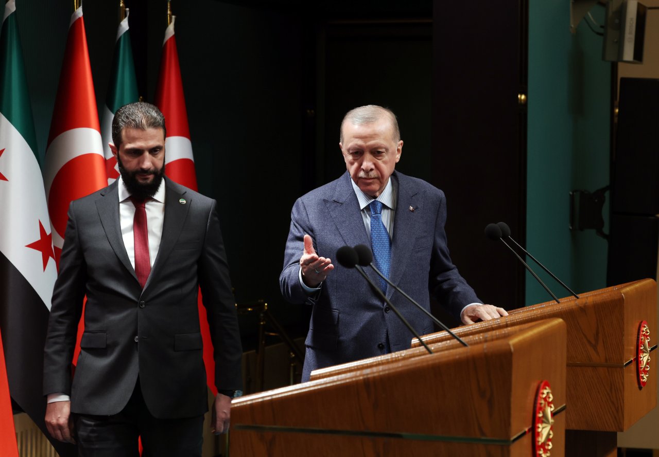 Cumhurbaşkanı Erdoğan ve Suriye lideri Ahmed Şara, Türk ve Suriye bayraklarının bulunduğu salonda kürsülerin yanında görülüyor.