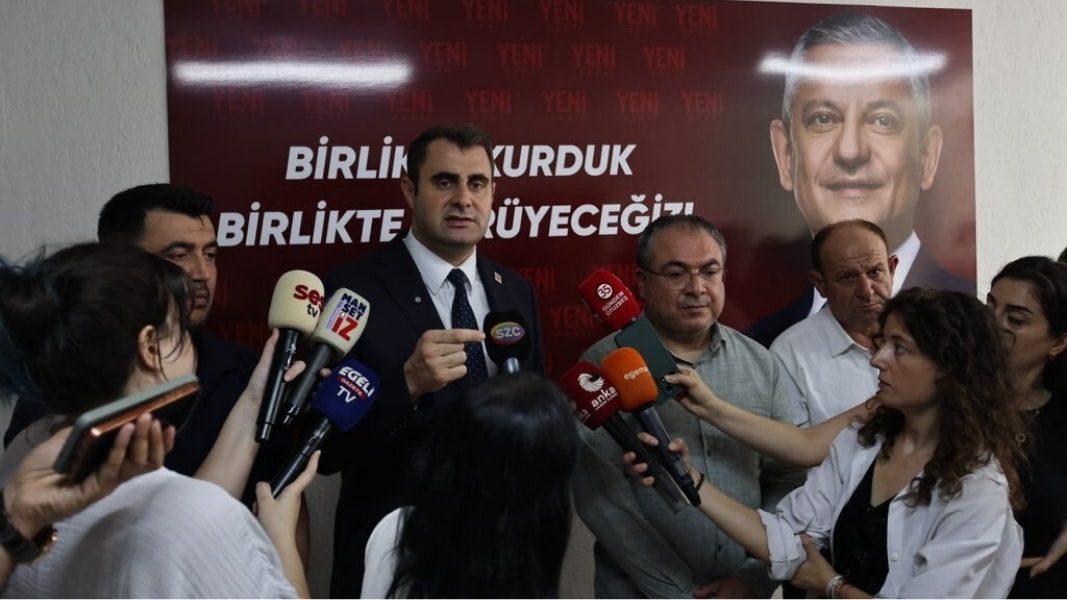 Çağatay Güç, parti binasında gazetecilere konuşurken mikrofonlar uzatılıyor.