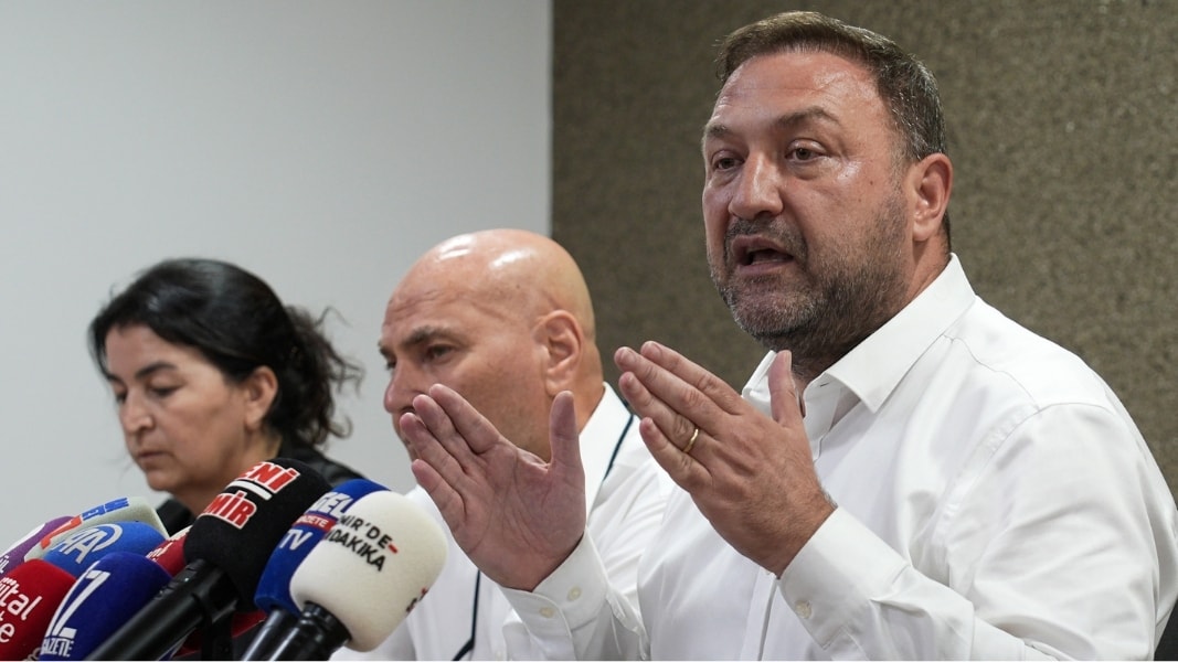 Utku Gümrükçü basın toplantısında mikrofonların önünde konuşuyor.