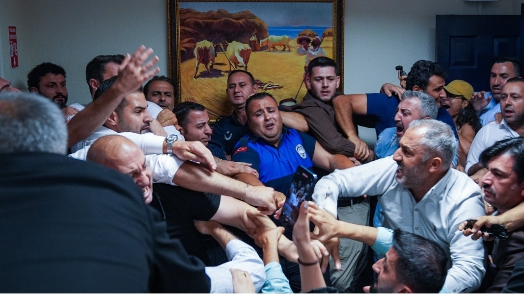 Menderes Belediye Meclisi'nde kalabalık bir grup arasında arbede yaşanırken güvenlik görevlileri araya giriyor.