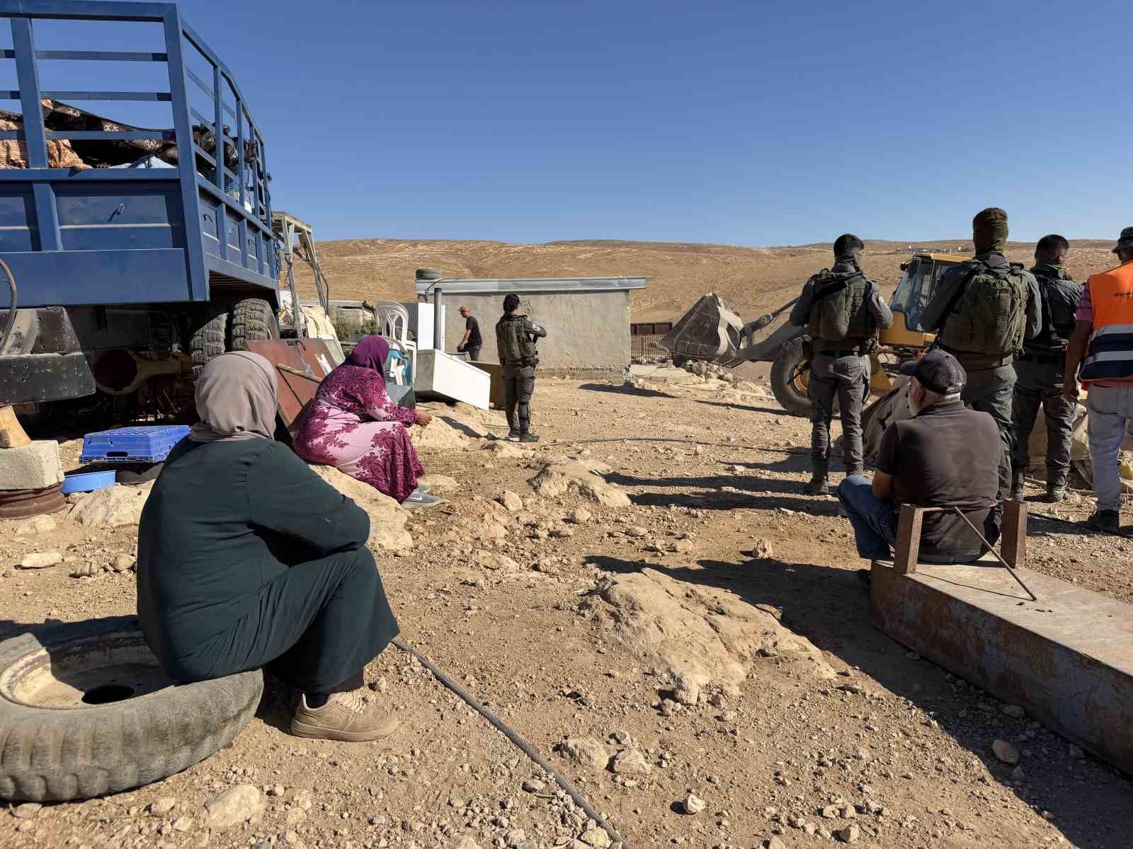 Al-Fakhit köyünde yıkım alanında bekleyen Filistinliler, İsrail askerleri ve iş makinesi.