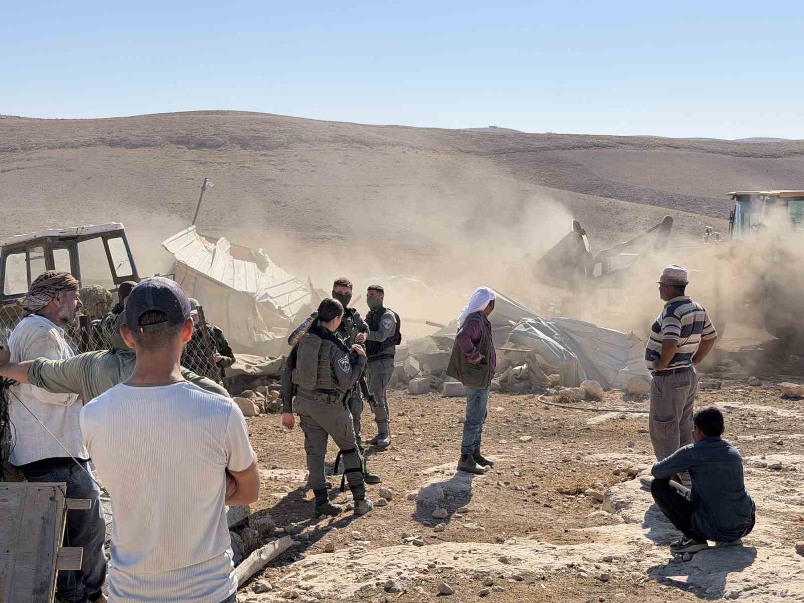 Yıkılan yapıların çevresinde İsrail askerleri ve Filistinlilerin bulunduğu tozlu alan.