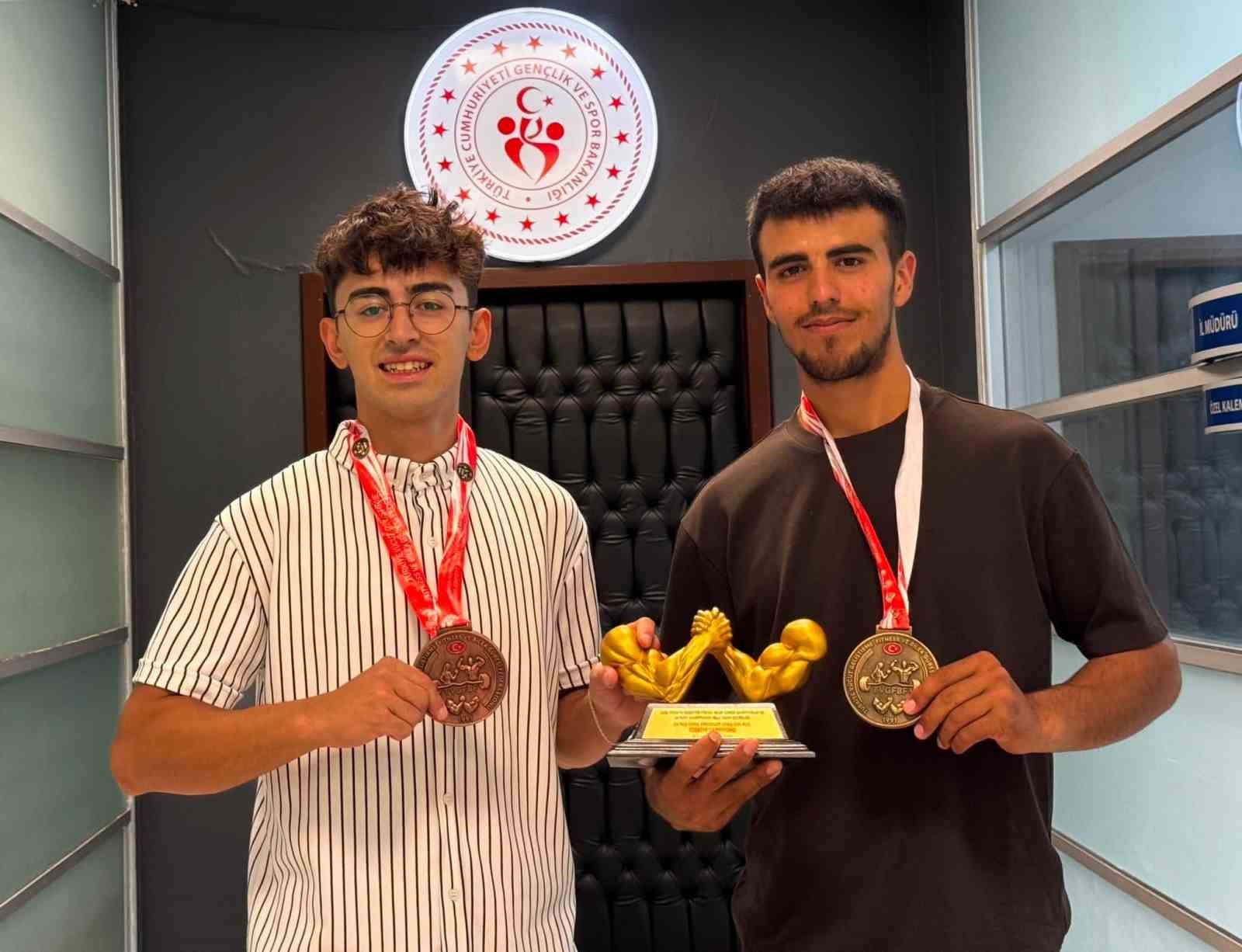 Madalya ve kupa taşıyan iki Kayserili bilek güreşi sporcusu.
