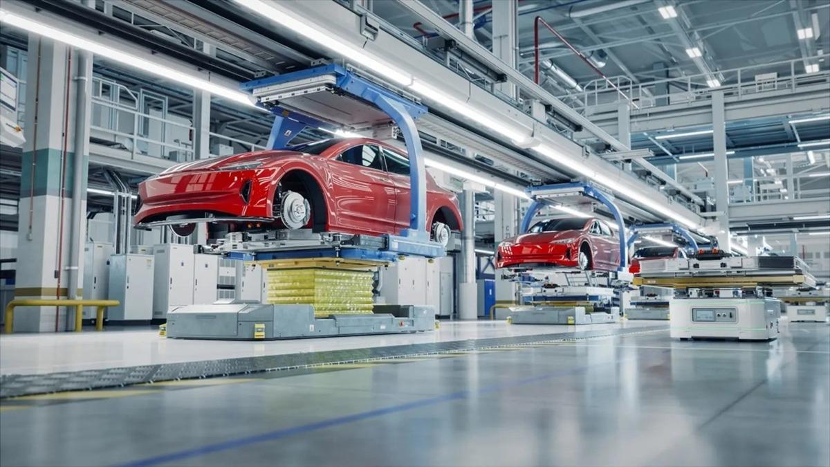 Modern bir otomobil üretim hattında kırmızı araç gövdelerinin görüldüğü fabrika görseli.