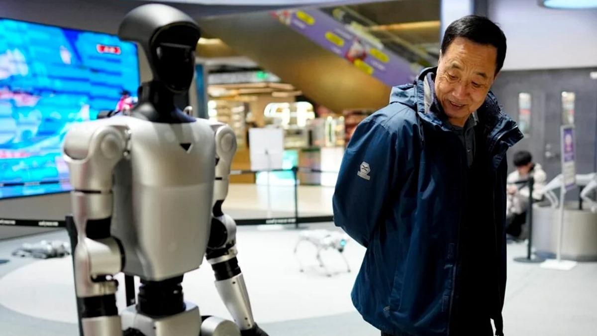 Bir sergi alanında insansı robotun yanında duran bir ziyaretçiyi gösteren görüntü.