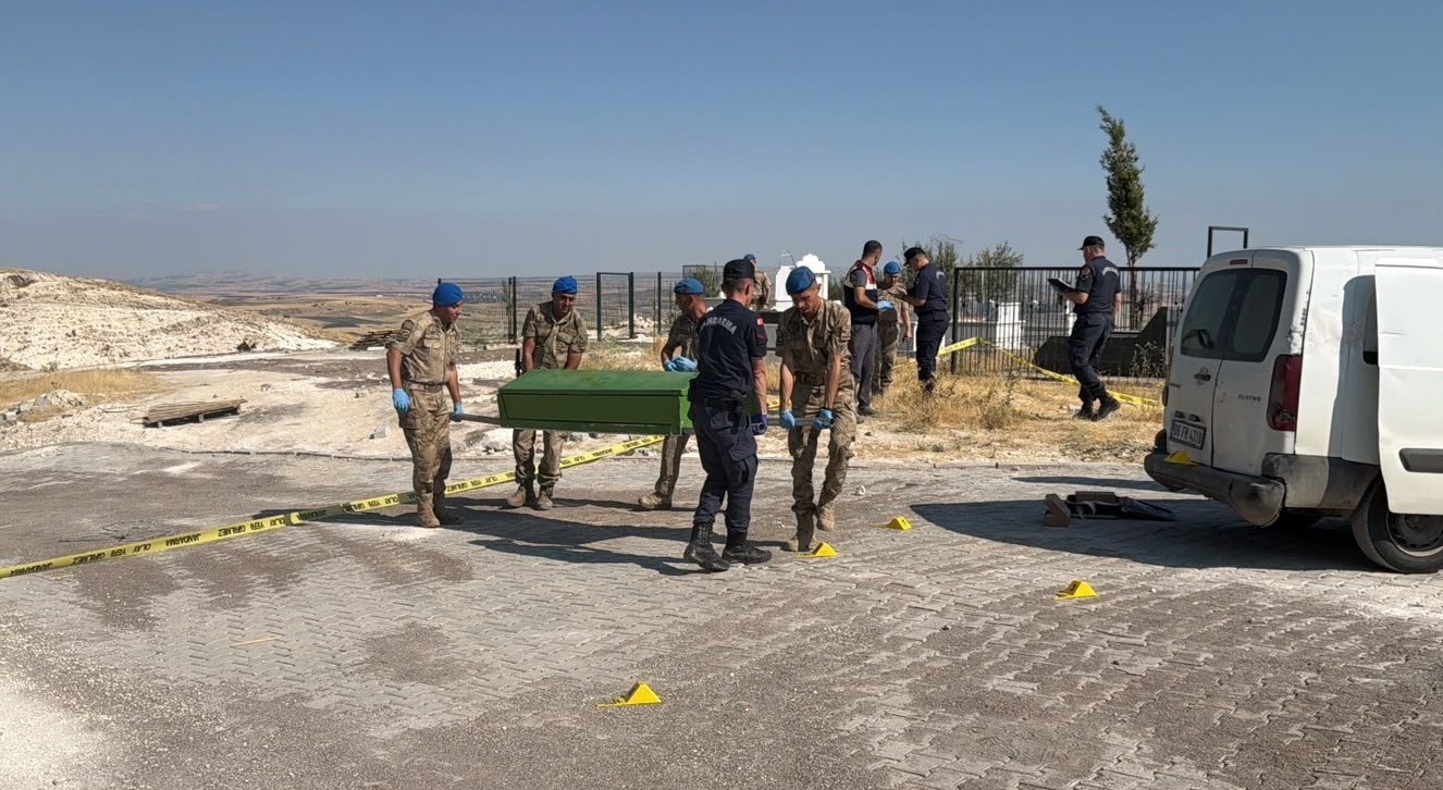 Görevliler, güvenlik şeridiyle çevrilen alanda cenazeyi taşıyor.