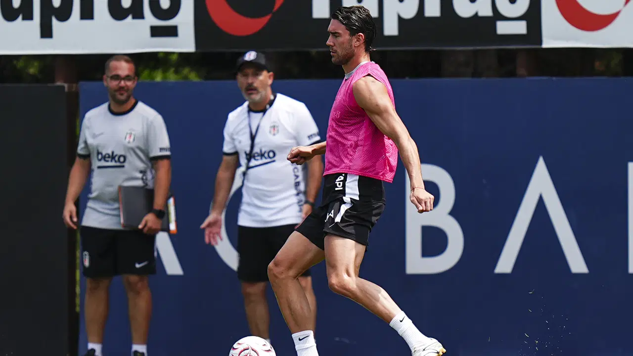 Dusan Vlahovic antrenmanda top kontrolü yaparken teknik ekip sahayı takip ediyor.