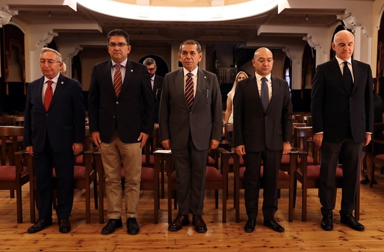 Galatasaray Lisesi salonunda protokol üyeleri Tevfik Fikret anma töreninde ayakta duruyor.