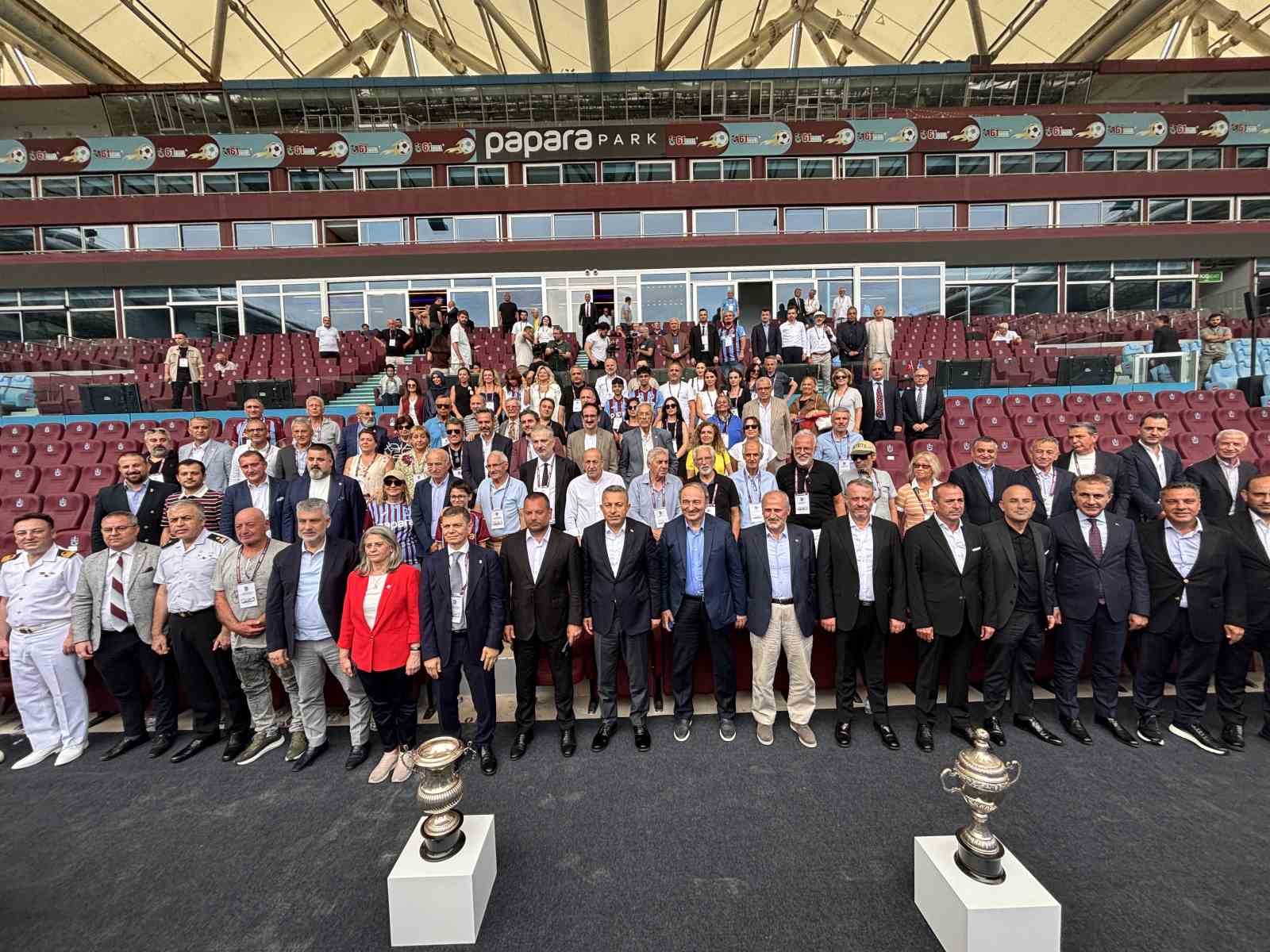 Trabzonspor stadyumunda geniş katılımlı grup fotoğrafı ve sergilenen kupalar.