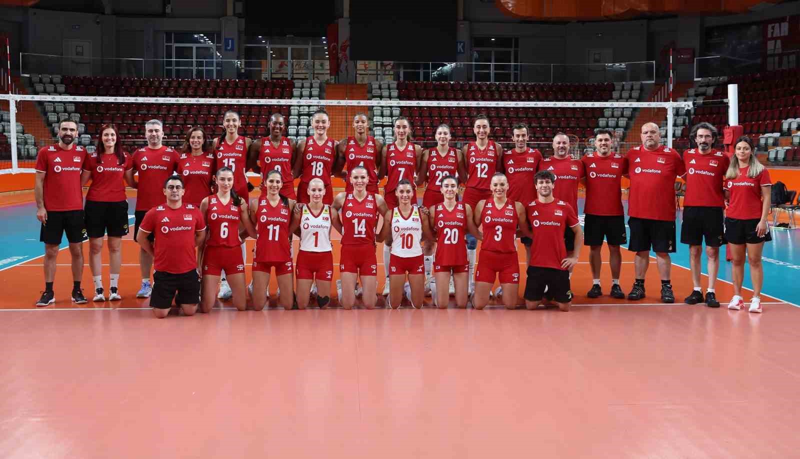 A Milli Kadın Voleybol Takımı oyuncuları ve teknik heyeti, voleybol sahasında takım fotoğrafı için poz veriyor.