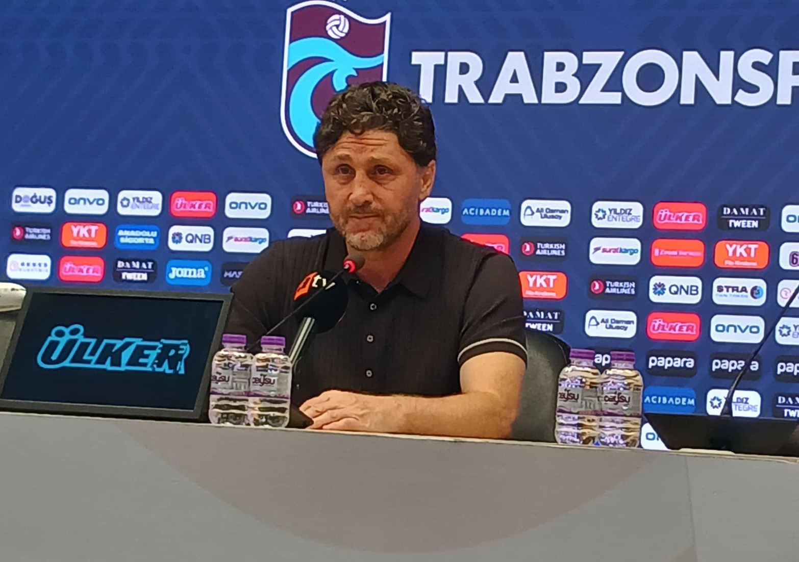 Fatih Tekke, Trabzonspor logolu basın toplantısı panosu önünde konuşuyor.