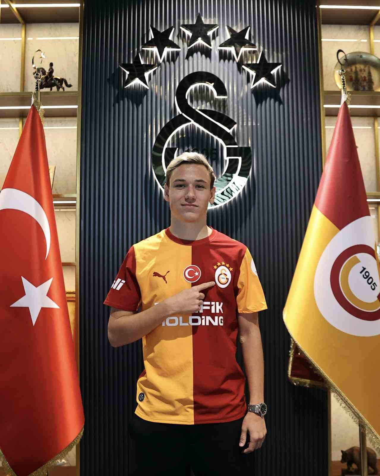 Aleksey Batrakov, Galatasaray arması önünde sarı-kırmızılı formayla poz veriyor.