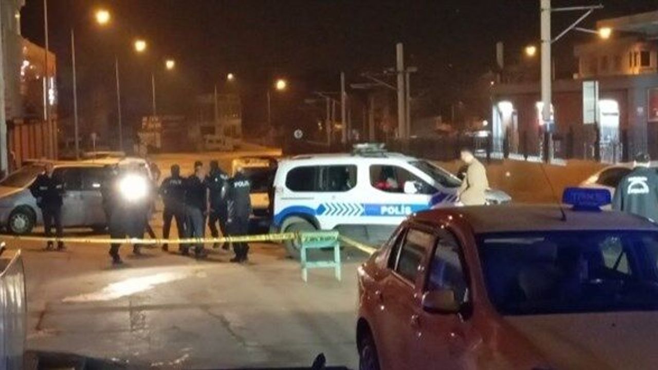 The scene of the incident surrounded by police vehicles and security tape at night.