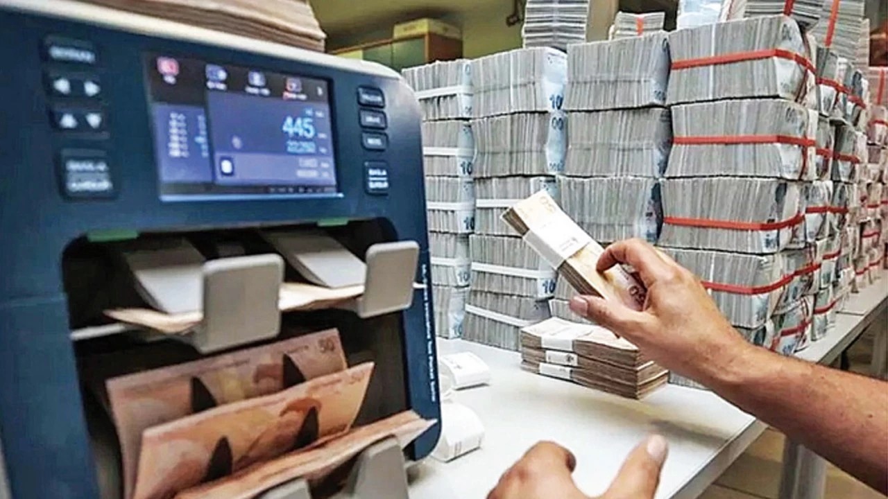 Para sayma makinesi ve deste deste Türk lirası banknotların bulunduğu banka ortamı.