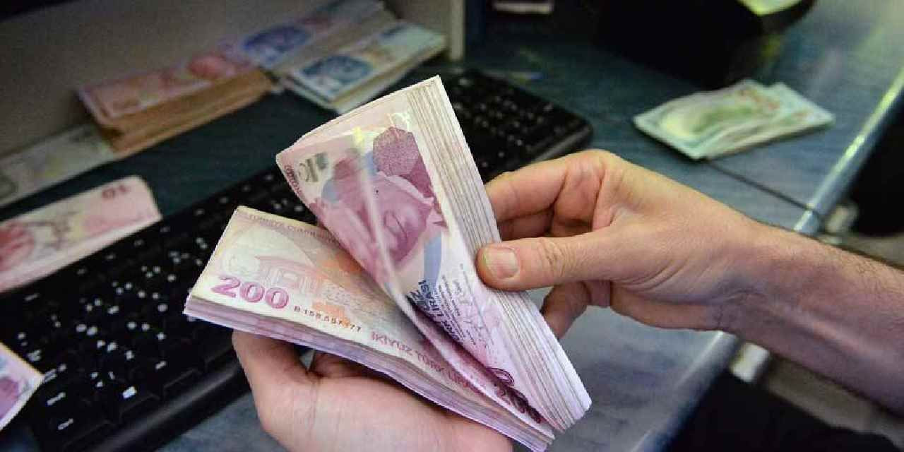 Banknotların elde sayıldığı ve bilgisayar klavyesinin görüldüğü bankacılık işlemi görseli.