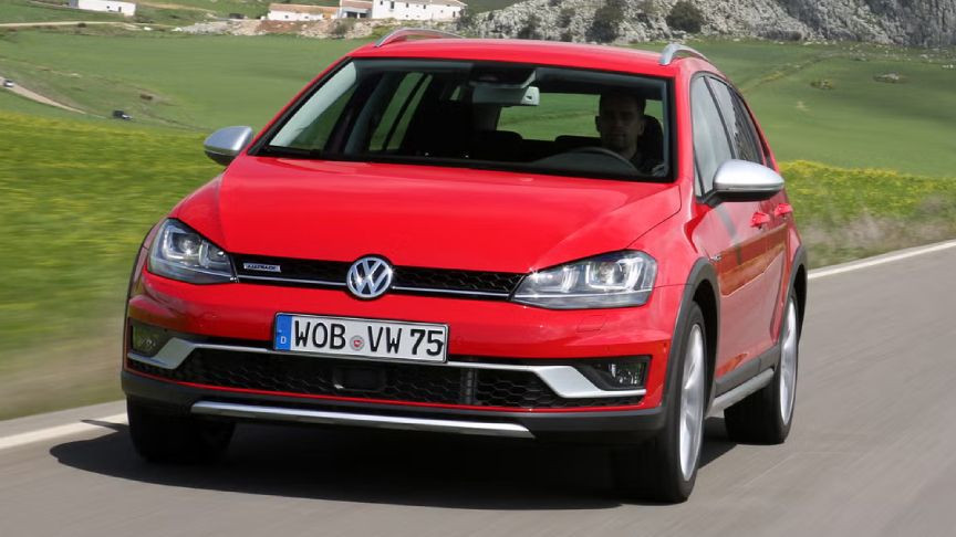 Kırsal yolda ilerleyen kırmızı Volkswagen Golf otomobil.