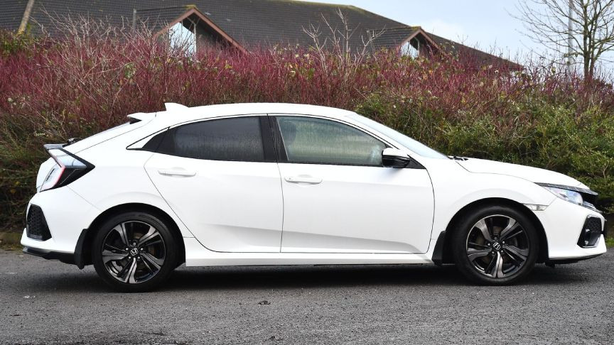 Yan profilden görülen beyaz Honda Civic hatchback otomobil.