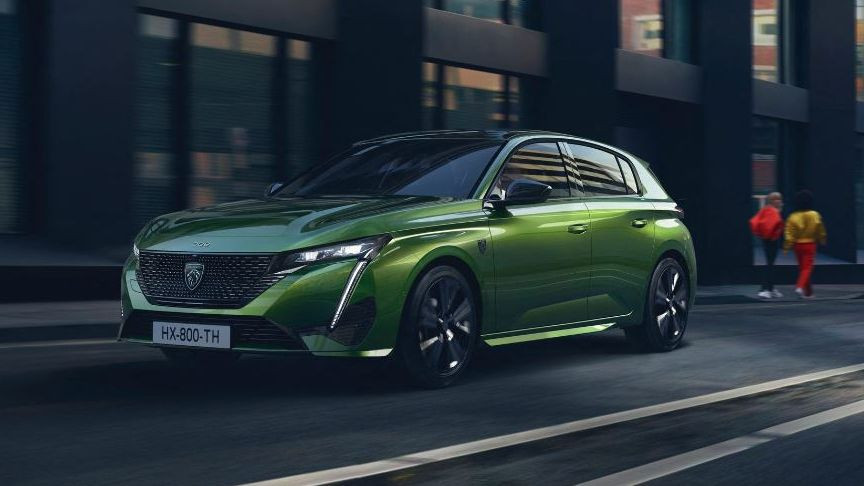 Şehir yolunda ilerleyen yeşil Peugeot 308 otomobil.