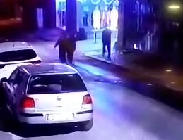 Güvenlik kamerasından alınmış yakın planda, gece aydınlatması altında yürüyen kişiler görünüyor.