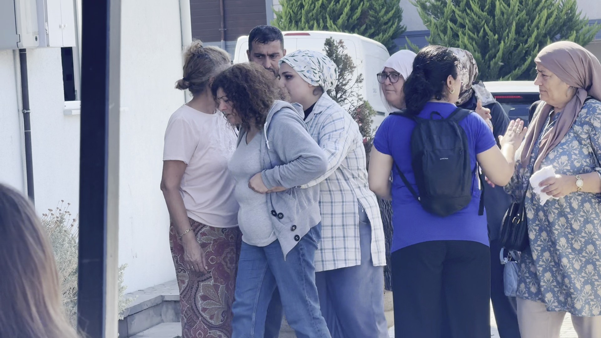 Bir binanın önünde toplanan ve üzüntü içinde olduğu görülen aile yakınları ve vatandaşlar.
