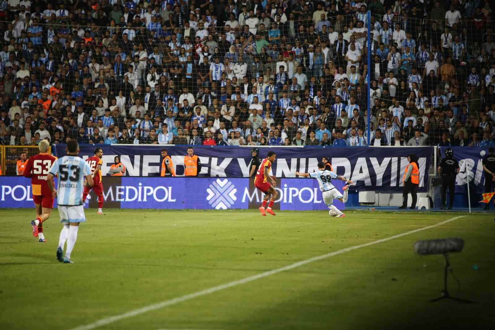 Saha kenarında oyun sürerken tribünlerde taraftarlar görülüyor.