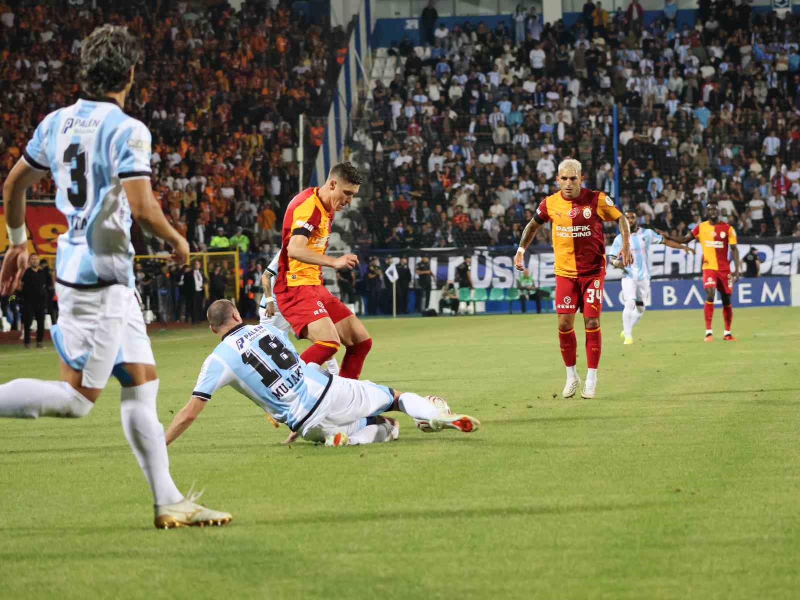 Galatasaraylı oyuncu, yerdeki Erzurumspor FK futbolcusunun yanında topu kontrol ediyor.