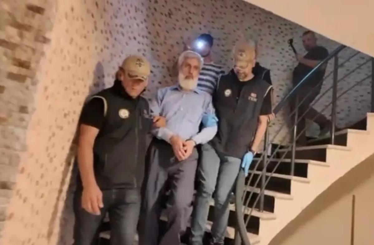 Alparslan Kuytul is led down the stairs accompanied by police teams.