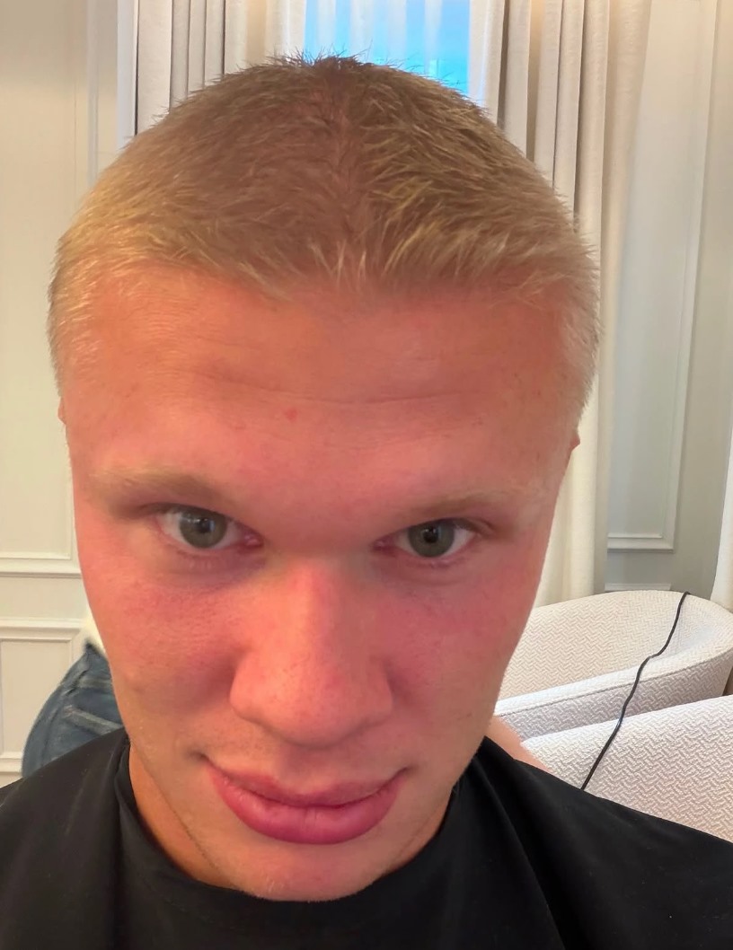 Erling Haaland guarda verso la telecamera in un primo piano con il suo nuovo look a capelli corti.