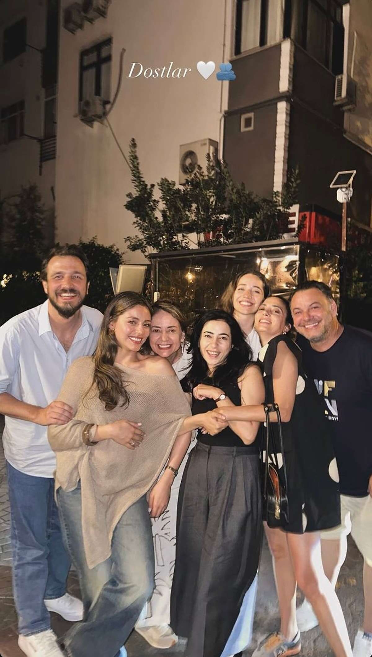 Bir grup oyuncunun gece dış mekanda birlikte verdiği fotoğraf ve üzerinde Dostlar yazısı.