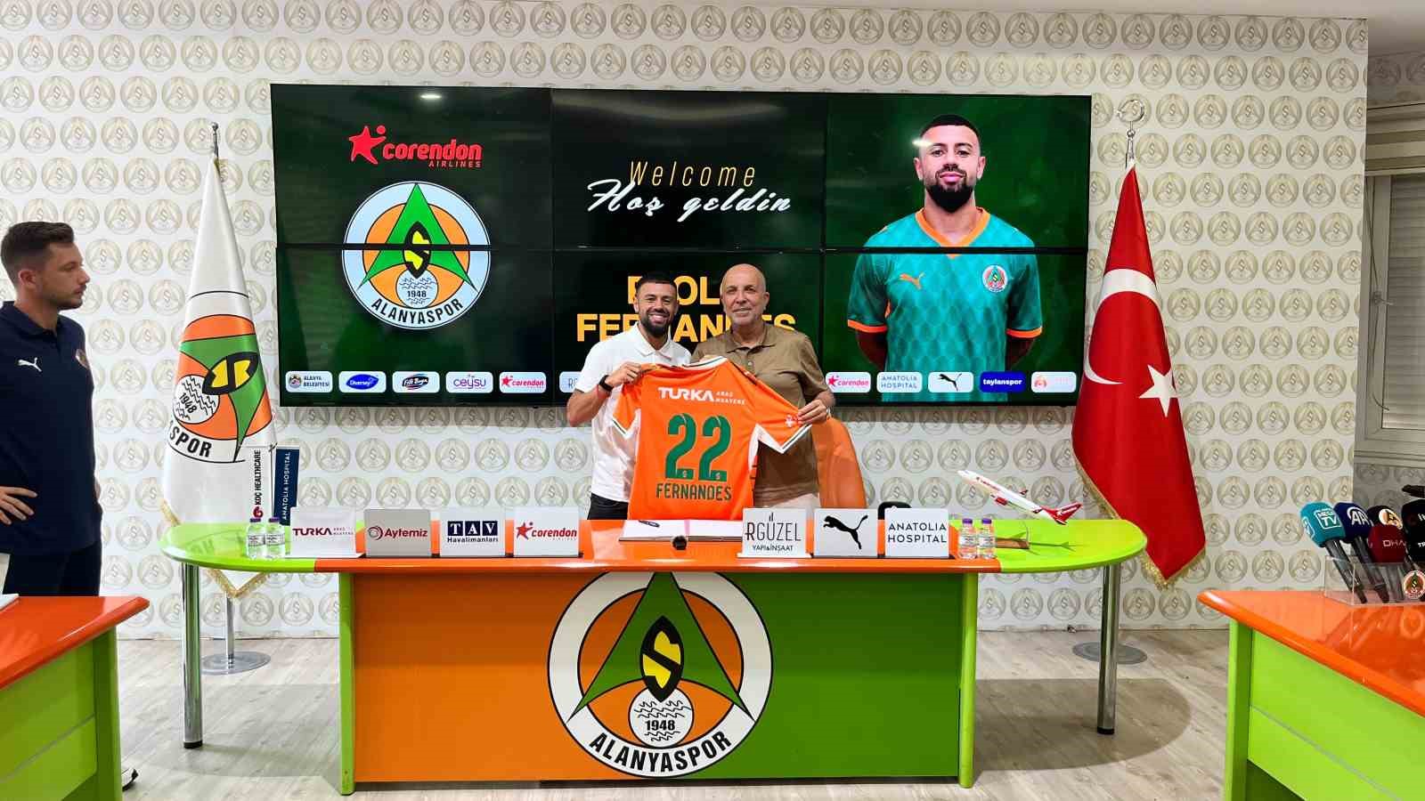 Paolo Fernandes e Hasan Çavuşoğlu posano davanti allo schermo di presentazione tenendo la maglia dell'Alanyaspor.