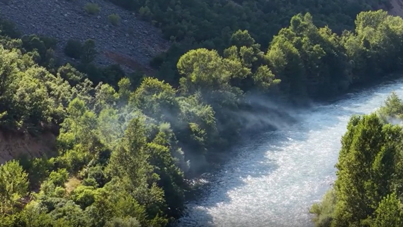 A natural view of smoke seen in a green wooded area by the river in Munzur Valley.