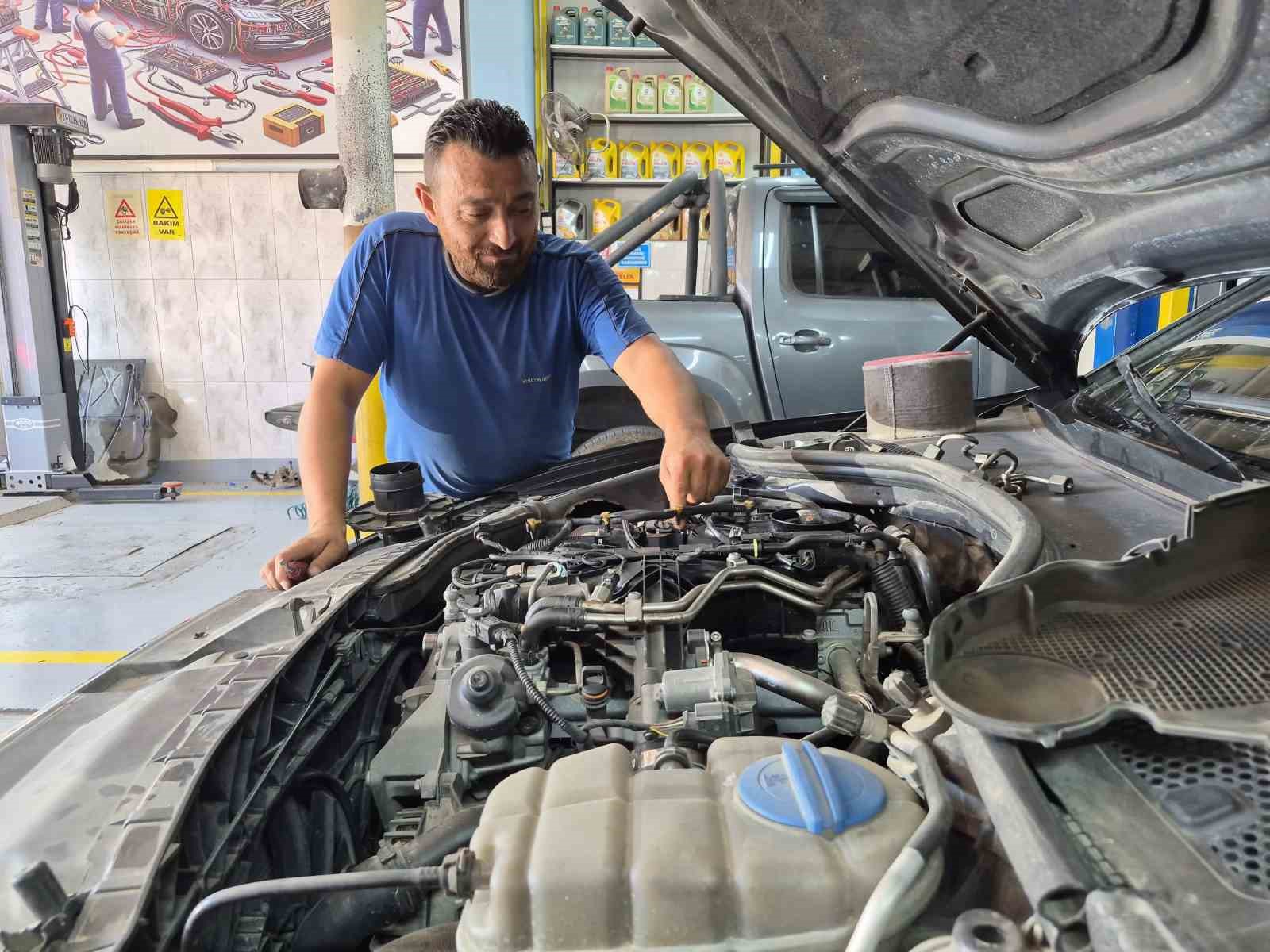Osman San, kaputu açık bir aracın motor bölümünde bakım yaparken görülüyor.