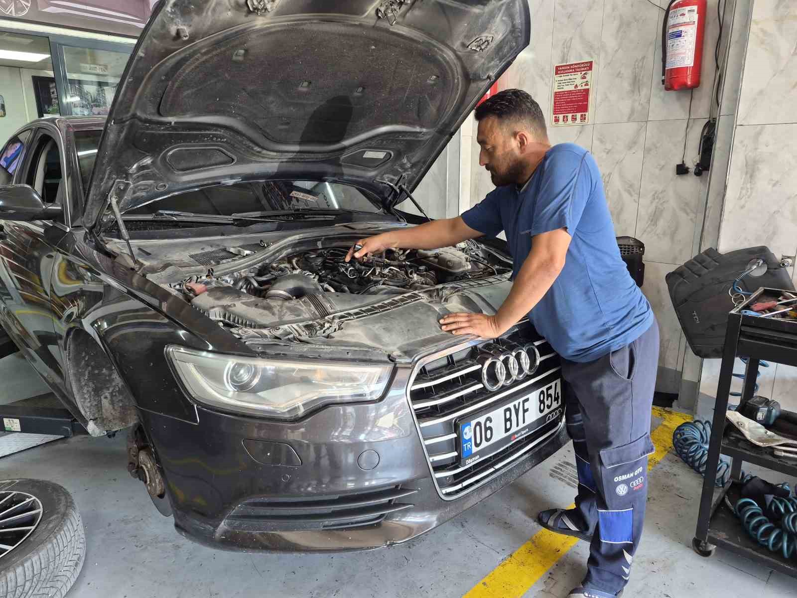 Bir otomobil servisinde kaputu açık araç üzerinde çalışan tamir ustası.