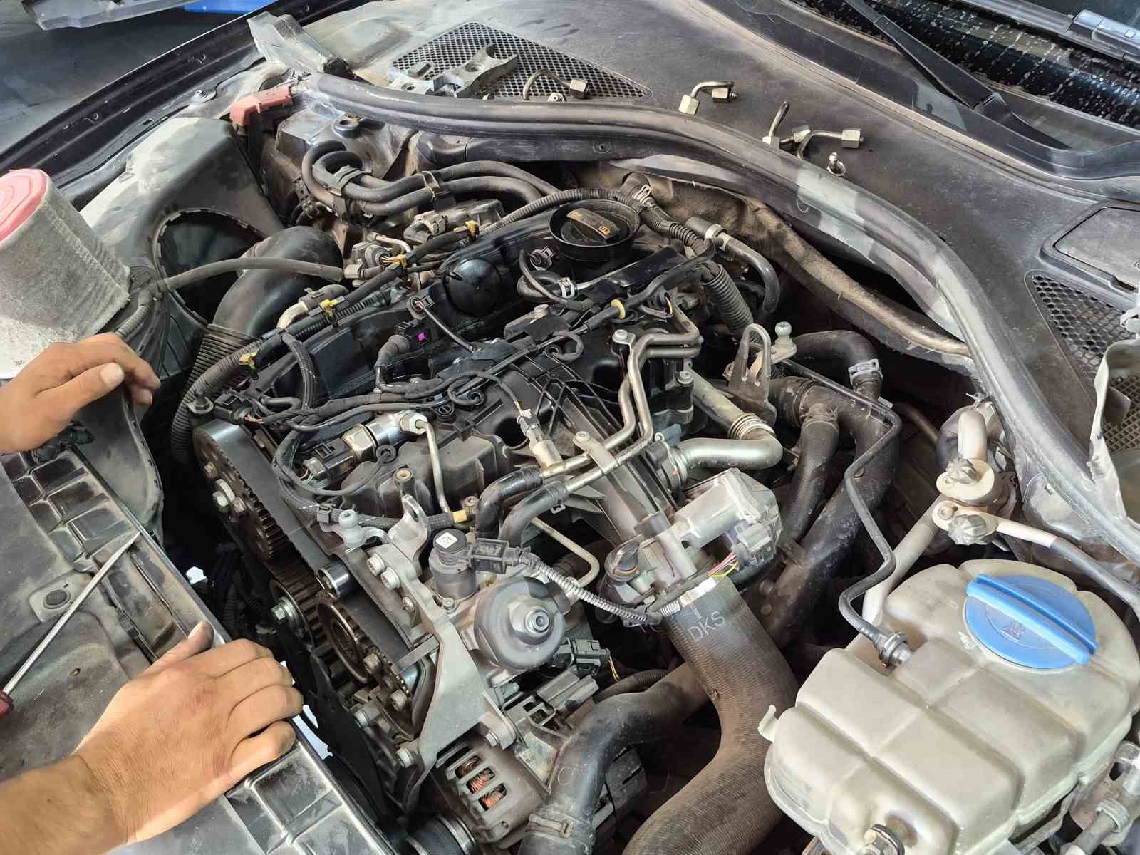 Kaputu açık bir aracın motor bölümü ve bakım yapılan parçalar görülüyor.