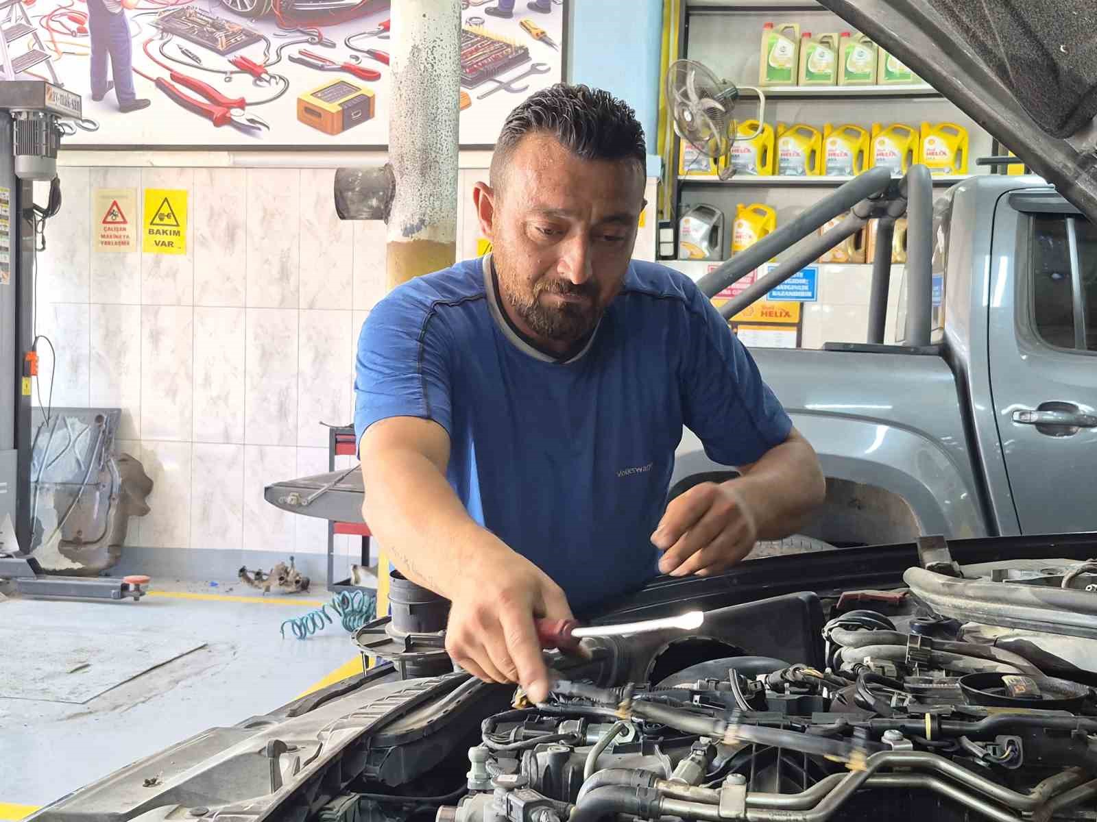 Osman San, araç motoru üzerinde aletle kontrol yaparken görülüyor.