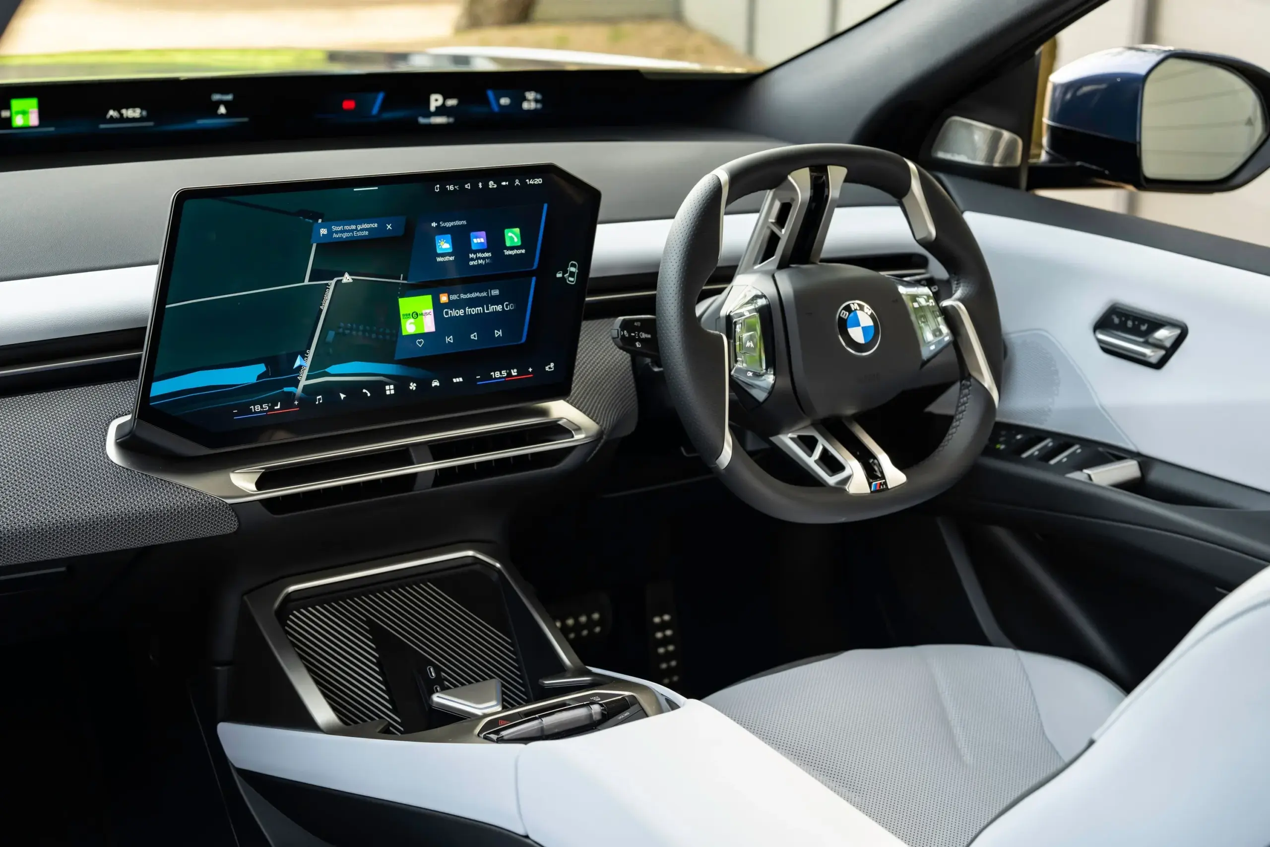 BMW araç iç kabininde dokunmatik ekran, dijital gösterge paneli ve direksiyon görünümü.